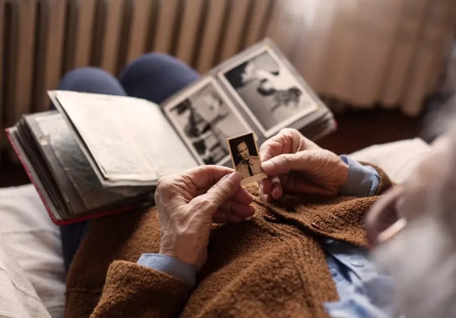 An older woman holding an old family photograph